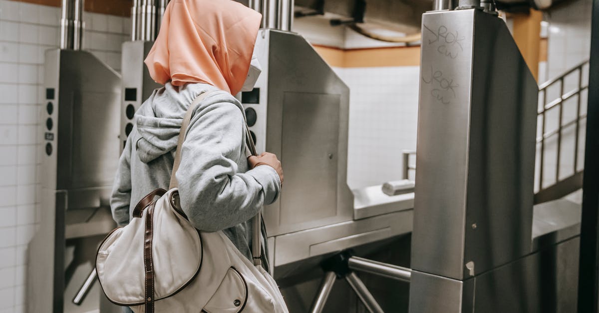 Is it safe to stand next to airport X-ray machines? - Side view of faceless Muslim female in casual outfit with protective mask and hijab in subway near turnstile with backpack