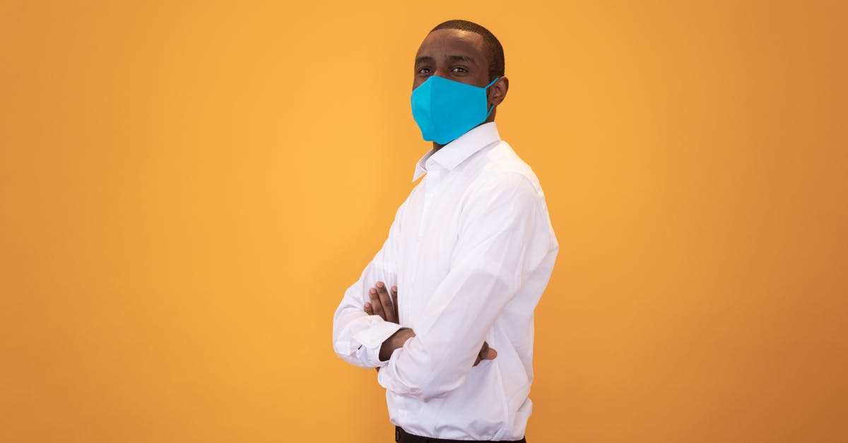 Is it safe to stand next to airport X-ray machines? - Black man in protective mask standing with crossed arms against yellow background