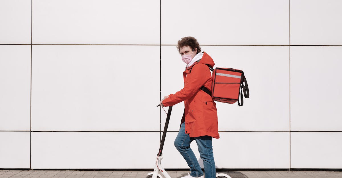 Is it safe to stay outside the Boulevard Périphérique in Paris? - Delivery Man Wearing a Face Mask and Riding a Scooter