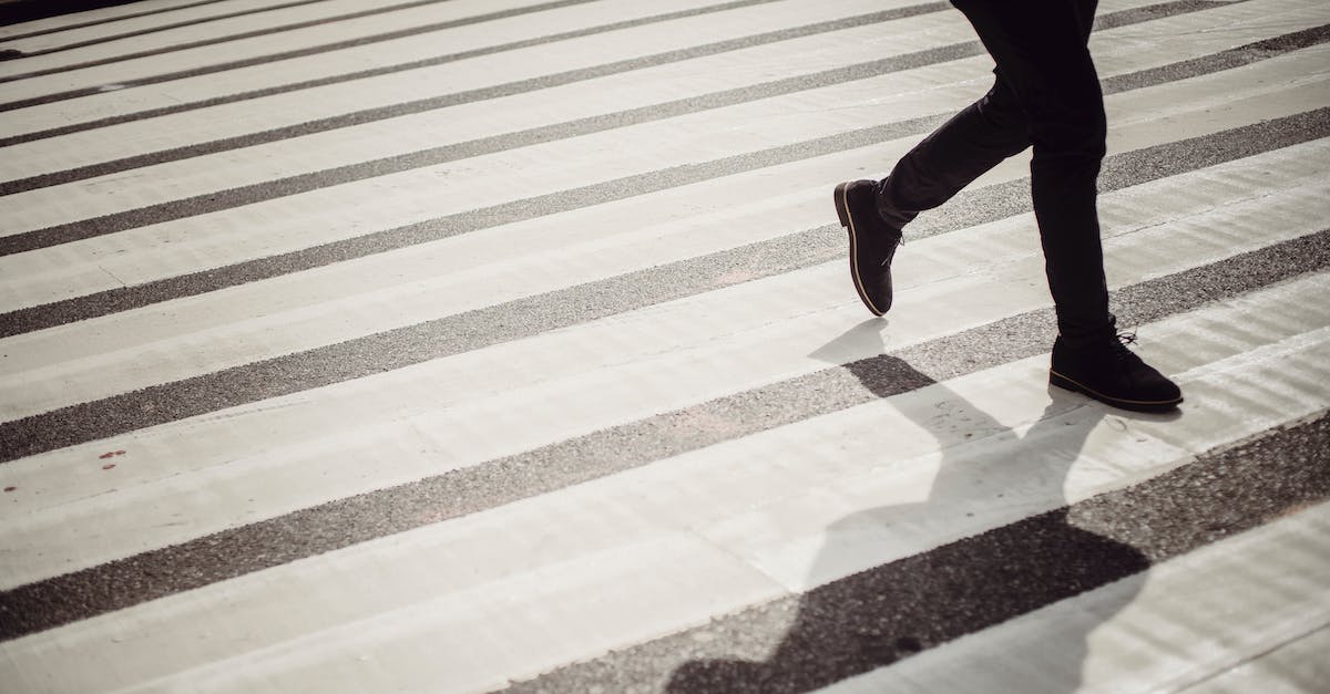 Is it safe to stay outside the Boulevard Périphérique in Paris? - Crop faceless person in elegant black trousers and shoes walking on crosswalk in daytime