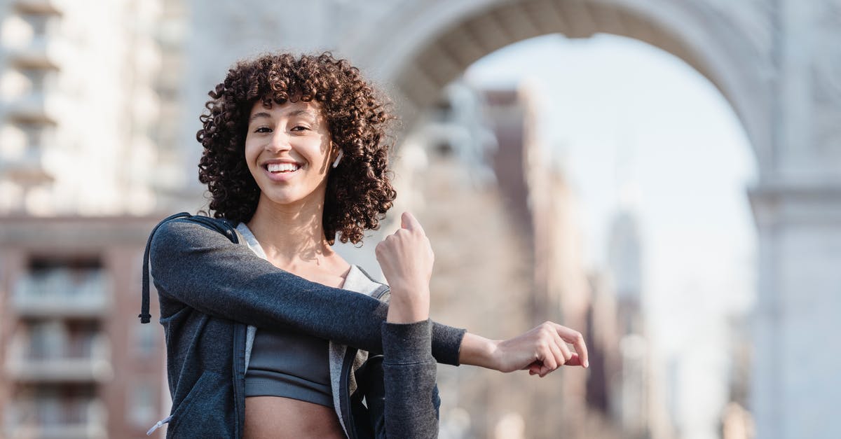 Is it true that Australia no longer issues physical visa stickers? - Delighted young ethnic female with Afro curls wearing sportswear stretching arms and listening to music in TWS earbuds while preparing for training