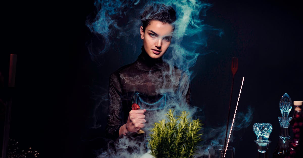 Is Pre-Check offered by Spirit Airlines? - Graceful young female alchemist with knife in hand in black outfit preparing potion from various herbs among smoke in dark room