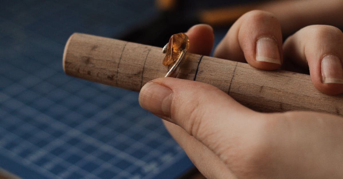 Is Qatar Airways' hand baggage size strictly enforced? - Person Holding a Silver Ring With Gemstone on a Wooden Tube