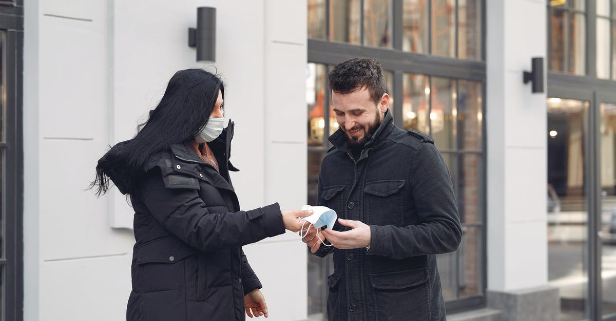 Is refund possible if I cannot take a (just rebooked) flight because of coronavirus bans? [duplicate] - Cheerful bearded man taking protective facial mask from girlfriend while standing together against city building facade during coronavirus pandemic at daytime