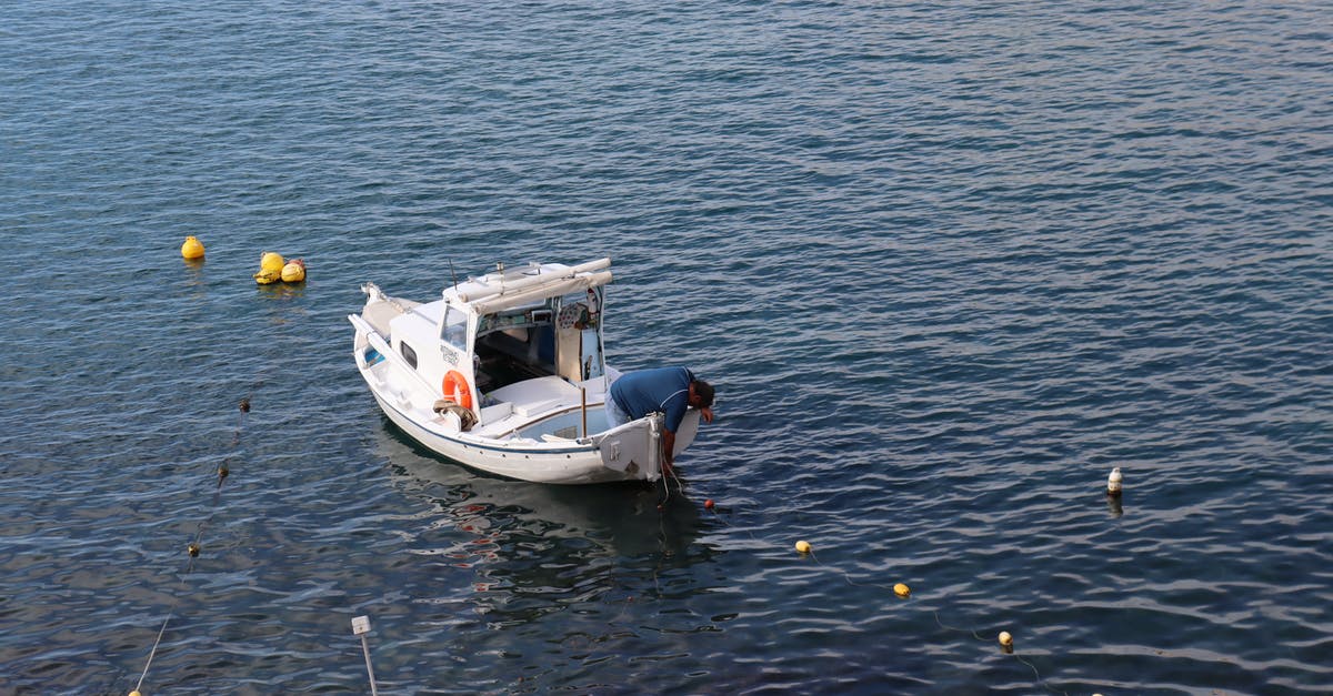 Is river travel to Vientiane and Phnom Penh recommended? - Man in Blue Shirt on White Fishing Boat