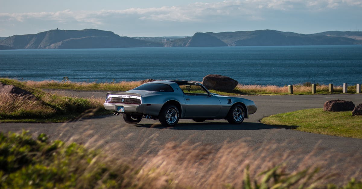 Is Route (F)35 Kjölur (still) considered a 4WD / mountain vehicle road? - Old vintage sports car casting shadow while driving on asphalt road surrounded by green meadow and large dark blue reservoir next to mountain valley in summertime