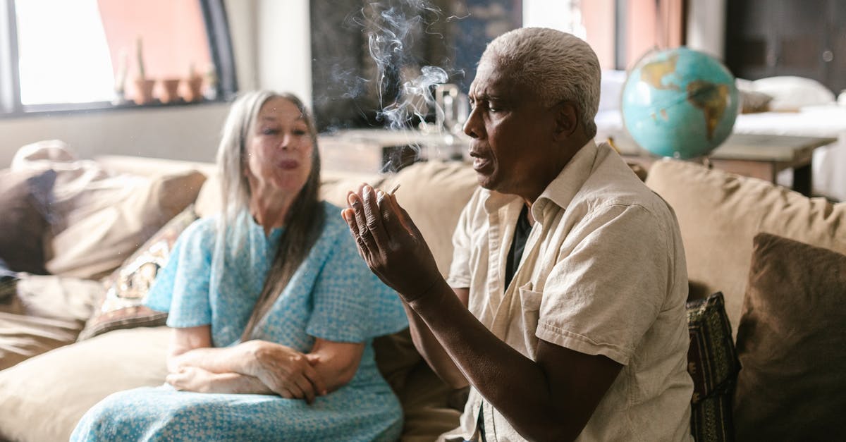 Is smoking weed legal or just tolerated in Colorado? - A Man Holding a Cigarette While Sitting on the Sofa
