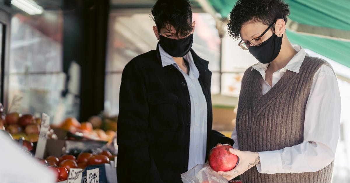 Is the Apple SIM pricing comparable to buying a local sim-card? - Concentrated young female friends in casual clothes and medical masks choosing fruits in local street food market on sunny day during coronavirus pandemic