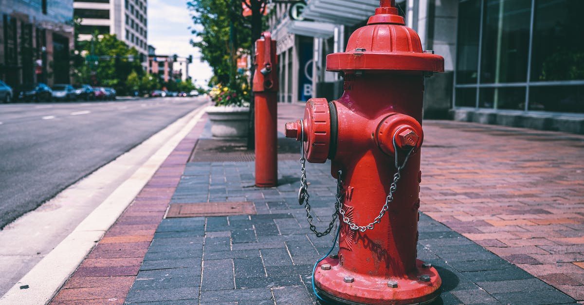 Is the area of Suresnes safe? - Red fire hydrant with chains located on empty street near road and building on sunny day