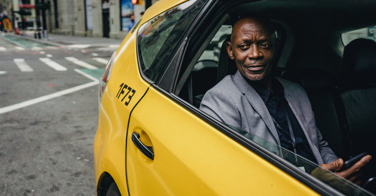 Is the Budapestcard worth the price if I use it for transport mainly? - Happy confident mature African American male looking away and expecting important message on mobile phone while sitting in yellow automobile