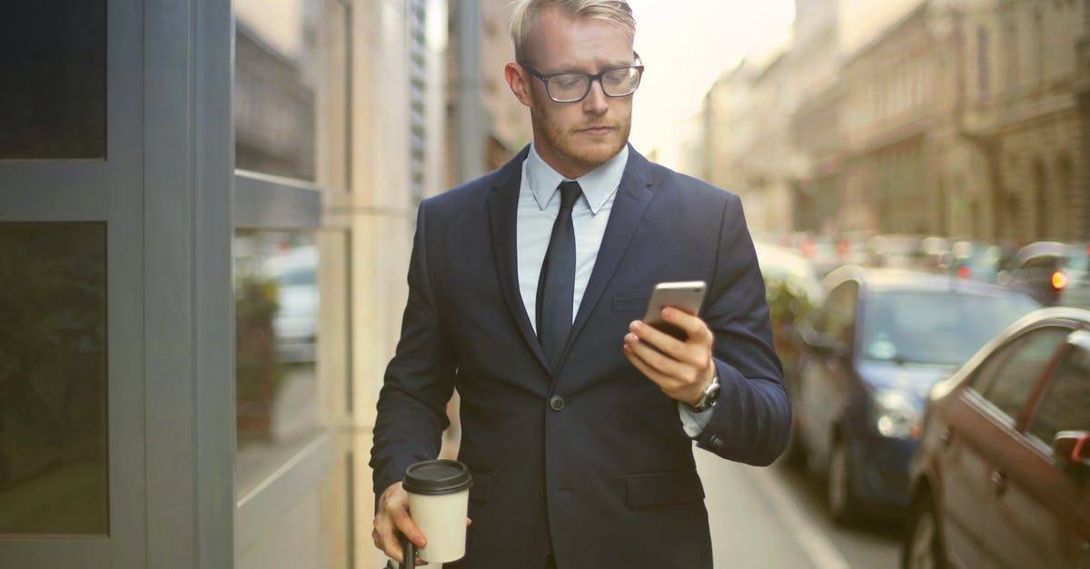 Is the carrying of knives in the street regulated in Malaysia? - Selective Focus Photo of Walking Man in Black Suit Carrying a To Go Cup and Briefcase While Using His Phone