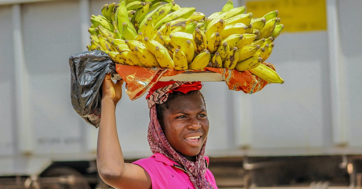 Is the carrying of knives in the street regulated in Malaysia? - Person in Pink Top Carrying Cluster of Bananas