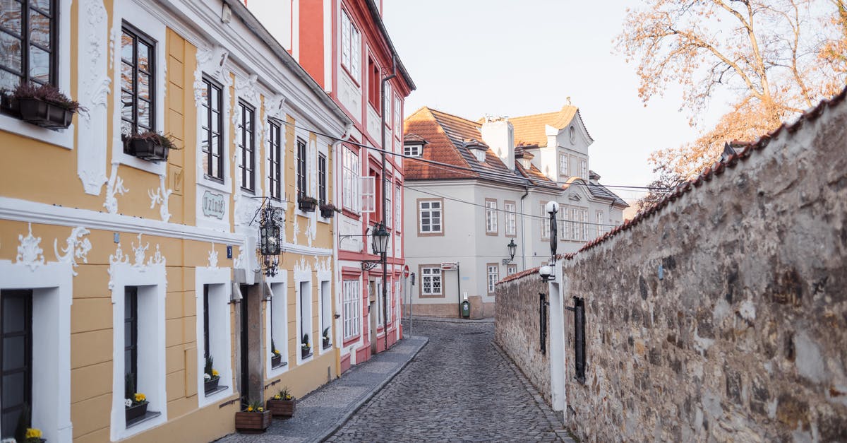 Is the Innsbruck to Prague sleeper train really direct? - Cobblestone walkway between stone wall and aged house exteriors with ornament in fall in Prague Czech Republic