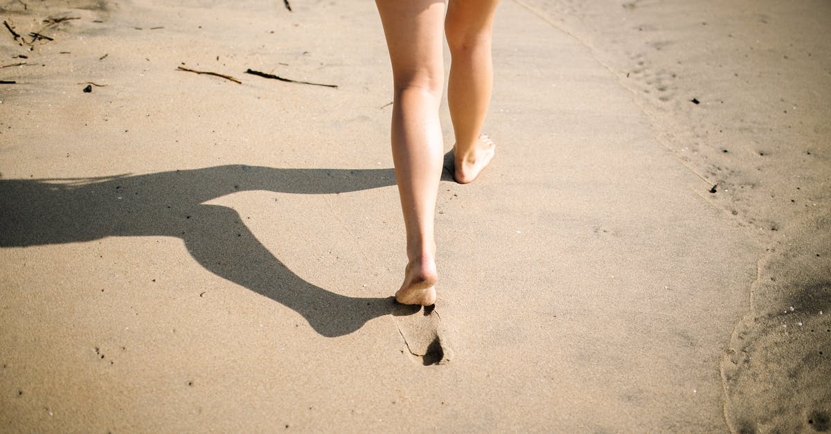 Is the last day of a thai visa included? - Woman in Blue Denim Shorts Walking on White Sand