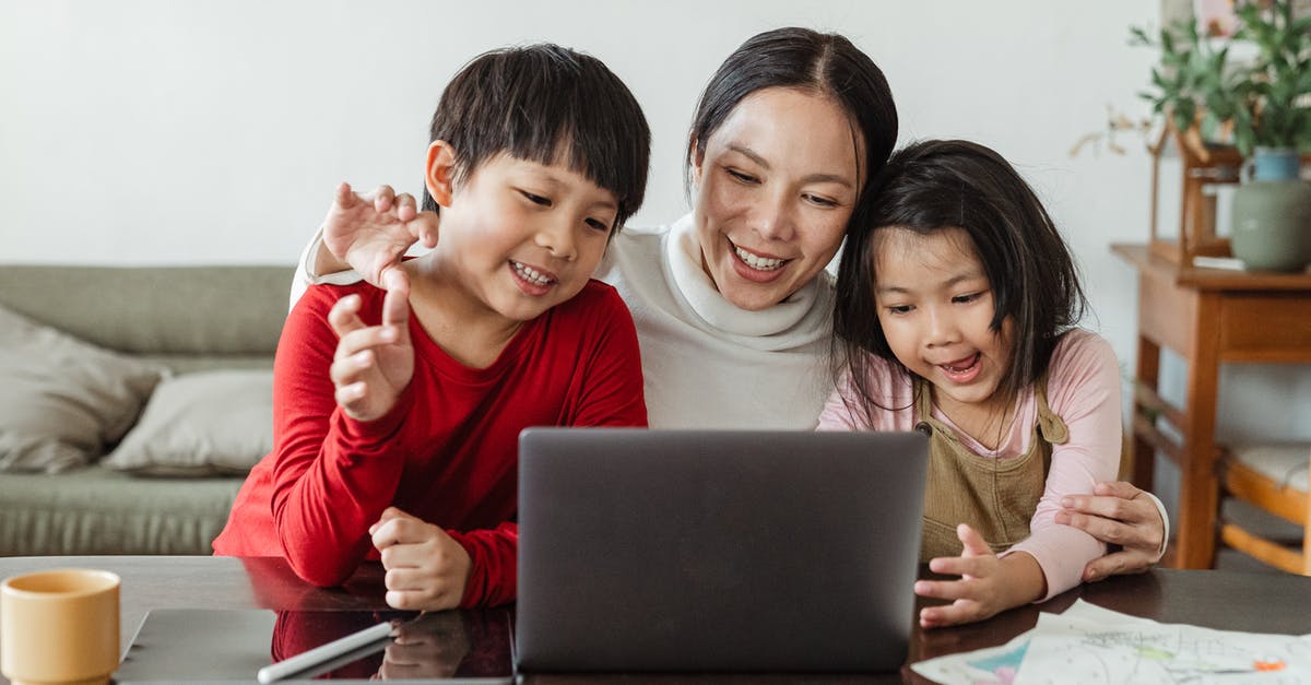 Is there a frequent flyer program catering to children? - Cheerful young Asian woman hugging little kids while watching entertaining program  together on laptop during weekend