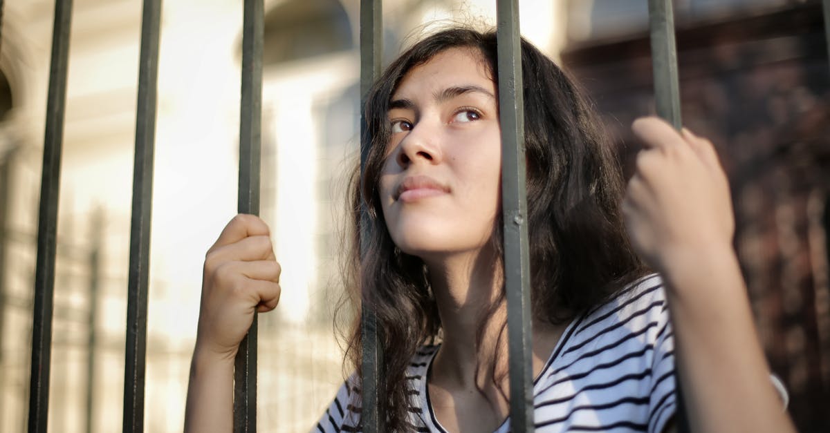 Is there a limit on bringing my videogames? - Sad isolated young woman looking away through fence with hope