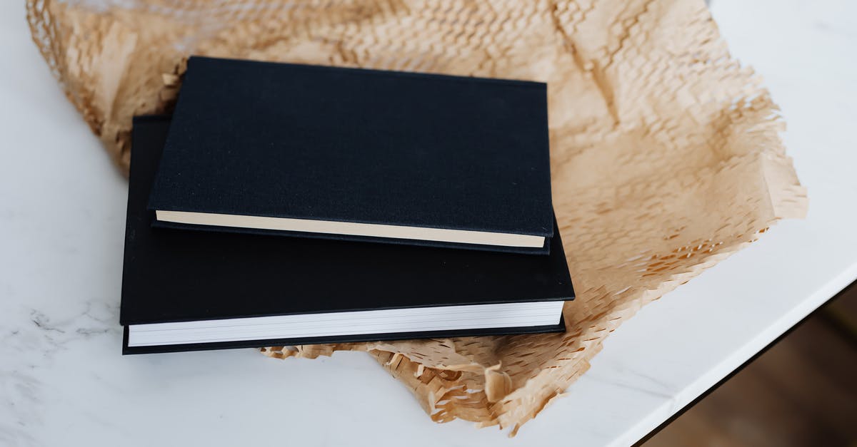 Is there a Post Office in Heathrow? - From above of notebook pair with black empty hardcover placed with packing paper and white marble table during prepare for postal delivery