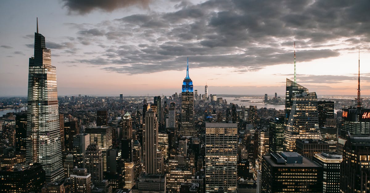 Is there a roof-top bar in the Empire State building? - Modern skyscraper exteriors against endless ocean under cloudy sky in New York City at sundown