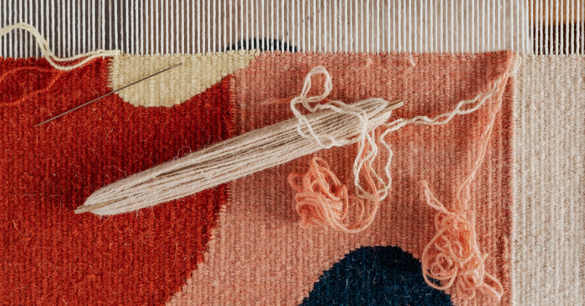 Is there a shuttle bus from Maastricht airport to Maastricht? - From above of shuttle and needle placed on part of handmade carpet with circle pattern on loom frame during weaving process