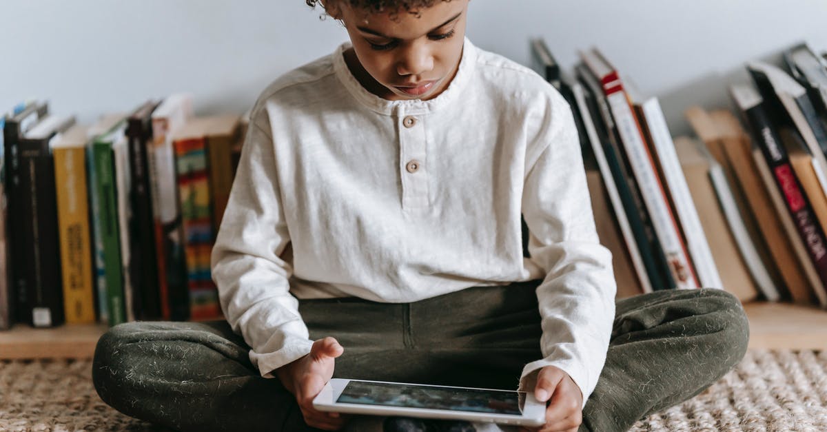 Is there a video game museum anywhere in Europe? - Crop black boy browsing tablet in room