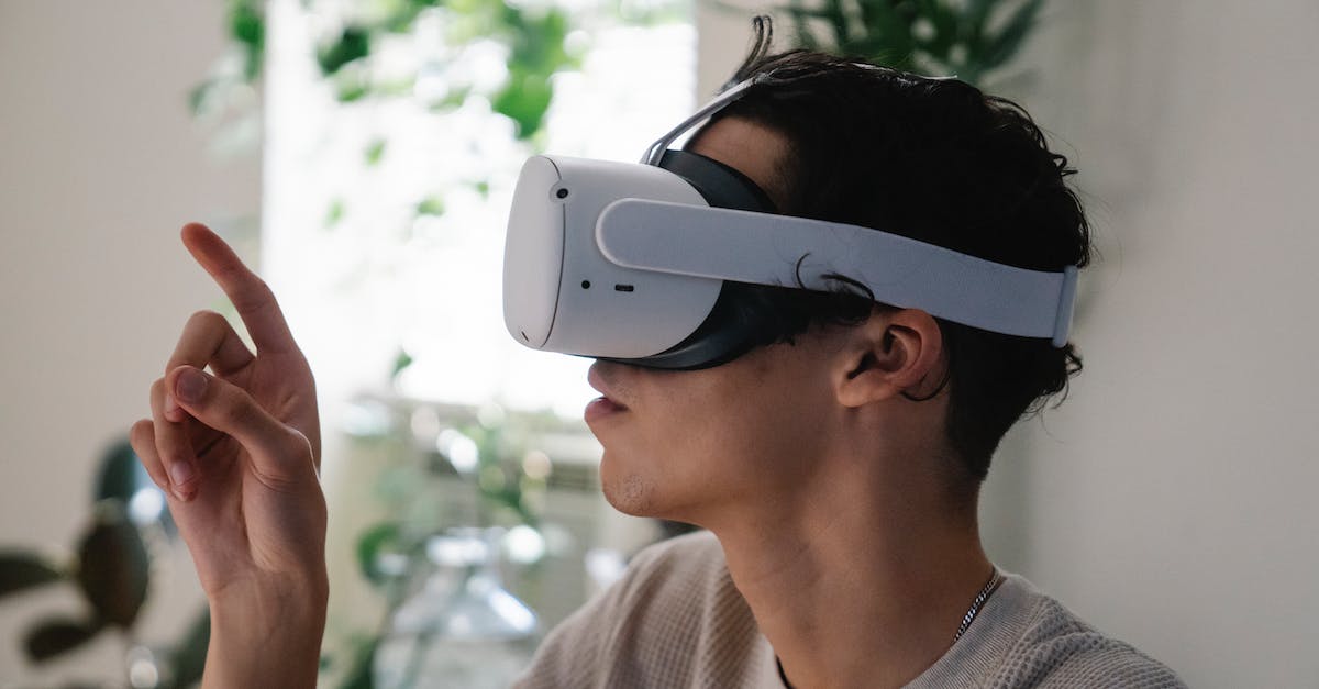 Is there a video game museum anywhere in Europe? - Side view of concentrated young guy in casual clothes experiencing virtual reality in modern headset at home