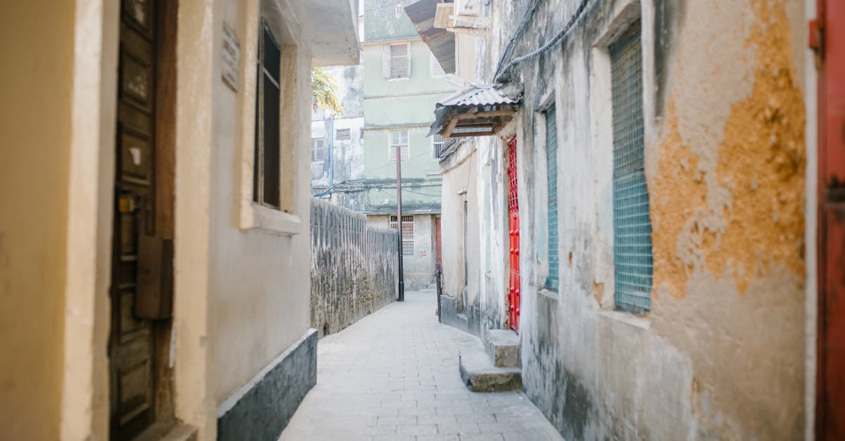 Is there a way to find out if there are Airbnbs in historic buildings that have been converted to condos? - Paved narrow street between aged stone residential houses with shabby facade in city