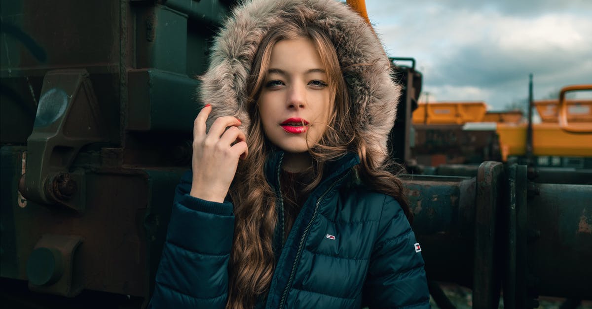 Is there a way to store stage luggage until needed? - Serious young woman in warm clothes standing on railway near train and looking at camera