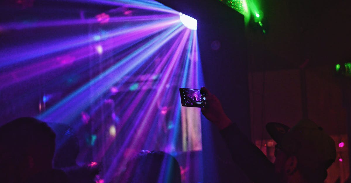 Is there an active nightlife in Seoul on weekdays? - Silhouettes of people in light of disco ball dancing in nightclub and man in cap taking photo