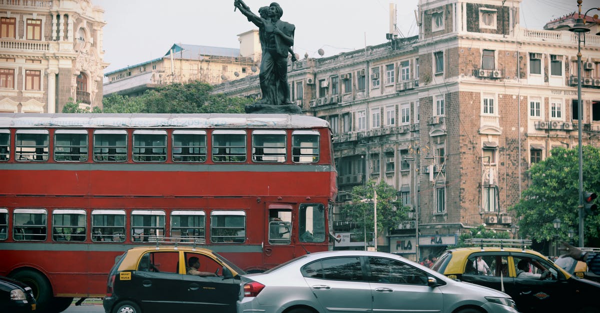 Is there any common website for Spanish intercity bus timetables? - Man in Black Jacket Standing Beside Silver Sedan Near Red Double Decker Bus