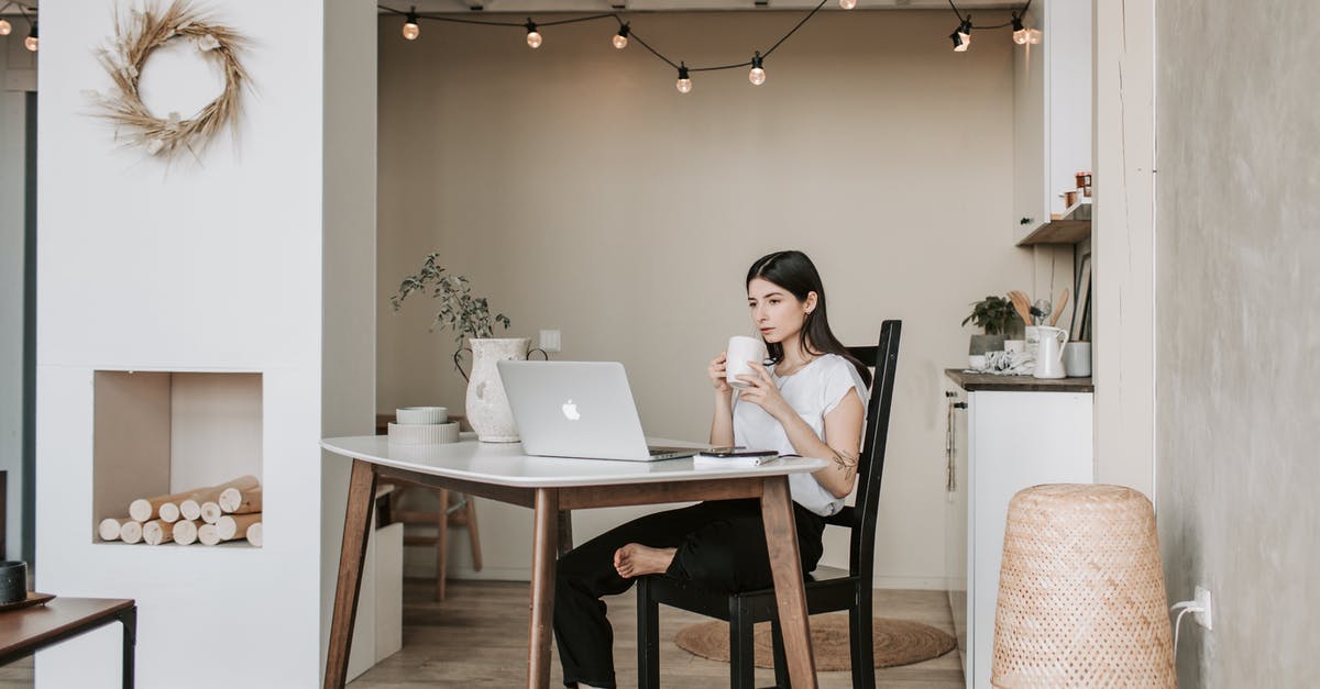 Is there any free WiFi network available at Nyaung-U Airport (NYU)? - Pensive young barefoot female sitting on chair with bending leg and watching video on laptop while resting and drinking hot coffee at table in modern light apartment