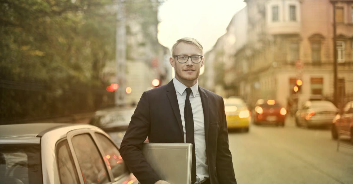 Is there any travel management software / webportal available? - Determined smiling businessman with laptop on street