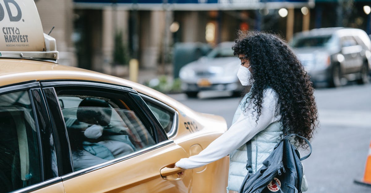 Is there any website or service for showing countries / regions open for travel during Covid-19 restrictions? - Side view of unrecognizable African American lady with long dark hair in casual clothes and medical mask opening door of ta parked on city street