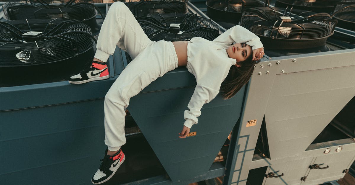 Is there camping gear specifically designed to fit modern air traveling? - Full body of stylish female with long hair looking at camera while lying with bent leg on edge of compressor air conditioner on roof