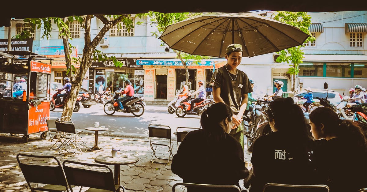 Is there ferry service from Vietnam to Borneo? - Man Standing Beside Umbrella Facing Three Women Sitting On Chairs