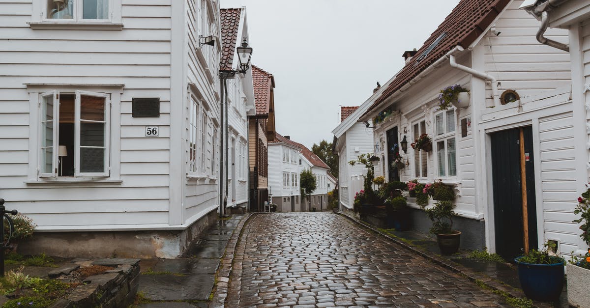 Is there hostel-like accommodation in the Krabi-Phuket area? - Narrow paved walkway on street between small residential buildings after raining in overcast weather