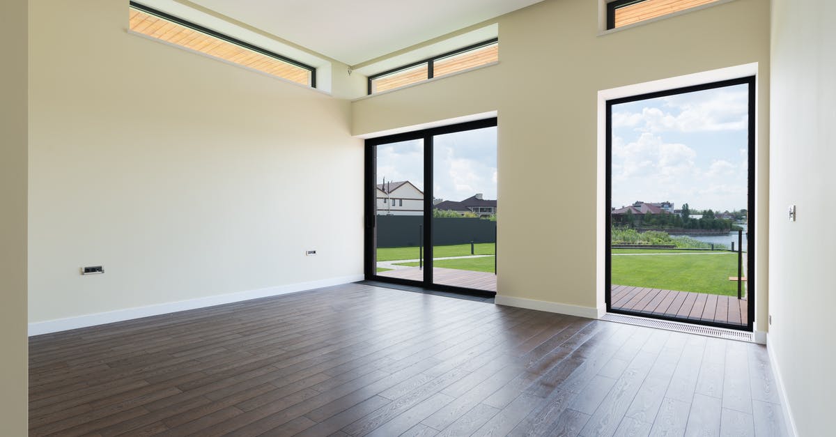 Is this an entry ban? - Interior of spacious room with wooden laminate floor big windows and glass door viewing terrace and green lawn