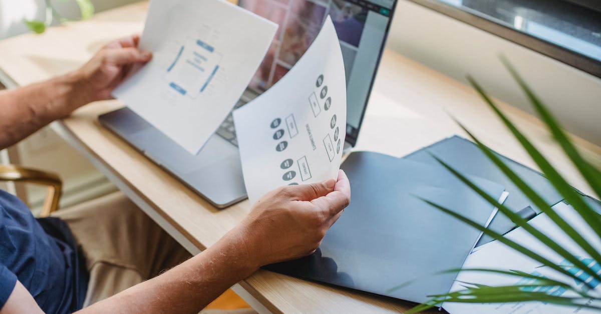 Is web check-in mandatory in German Wings? - Crop anonymous male designer in casual wear sitting at table with opened laptop and folders and reading papers