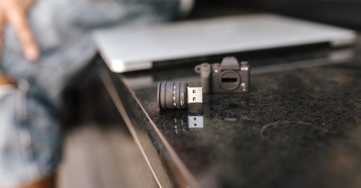 Issues powering a US laptop in Europe, via an adapter - Crop anonymous male sitting on stone bench with modern netbook and portable contemporary USB adapter