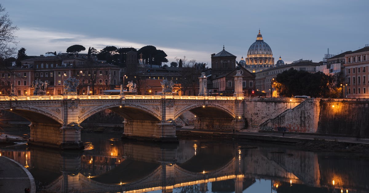 Italian equivalent to French St. Tropez or Spanish Marbella? - Old urban bridge reflecting in river in evening city