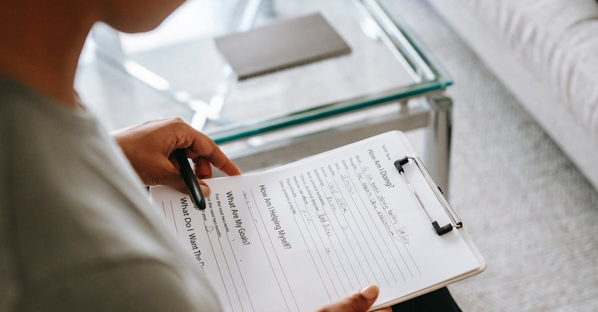 Italian Schengen visa form session expired - From above of blurred anonymous female psychologist reading documents on clipboard while sitting in office near table during session