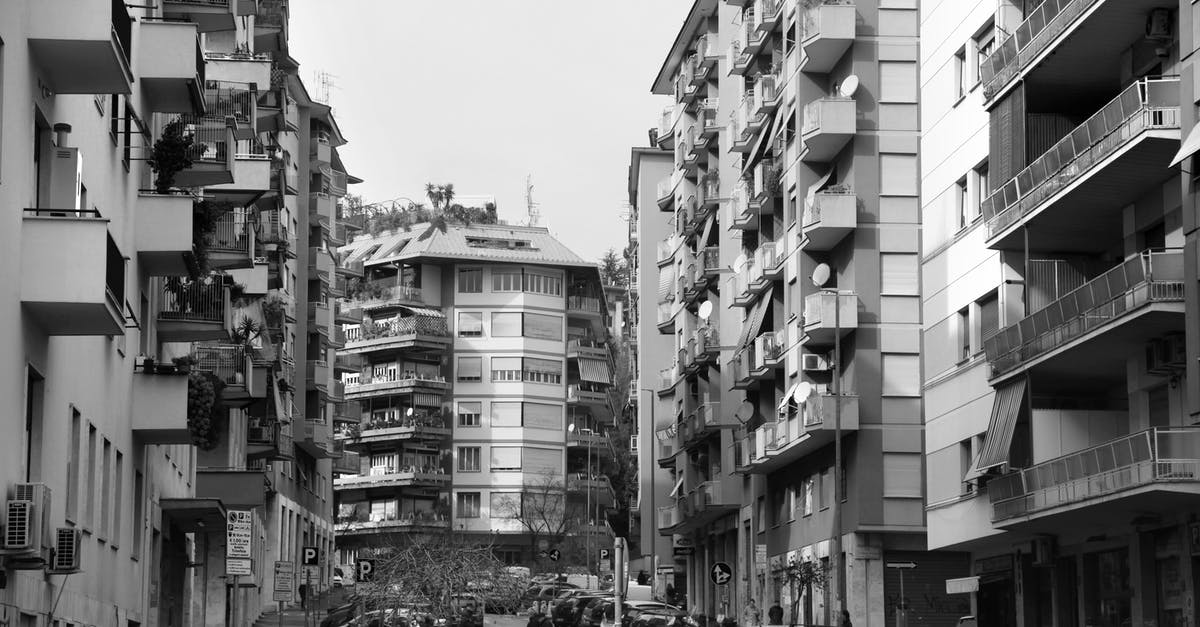 Italy Regional Trains itinerary and routes - Black and white of residential district of Rome with typical buildings and various cars parked on narrow asphalt road