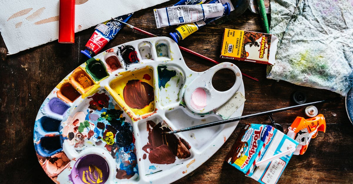 Item for removing stuff from headphone jack on a plane? - Top view of various art supplies including paintbrushes with colorful tubes of paint and palette placed on wooden table