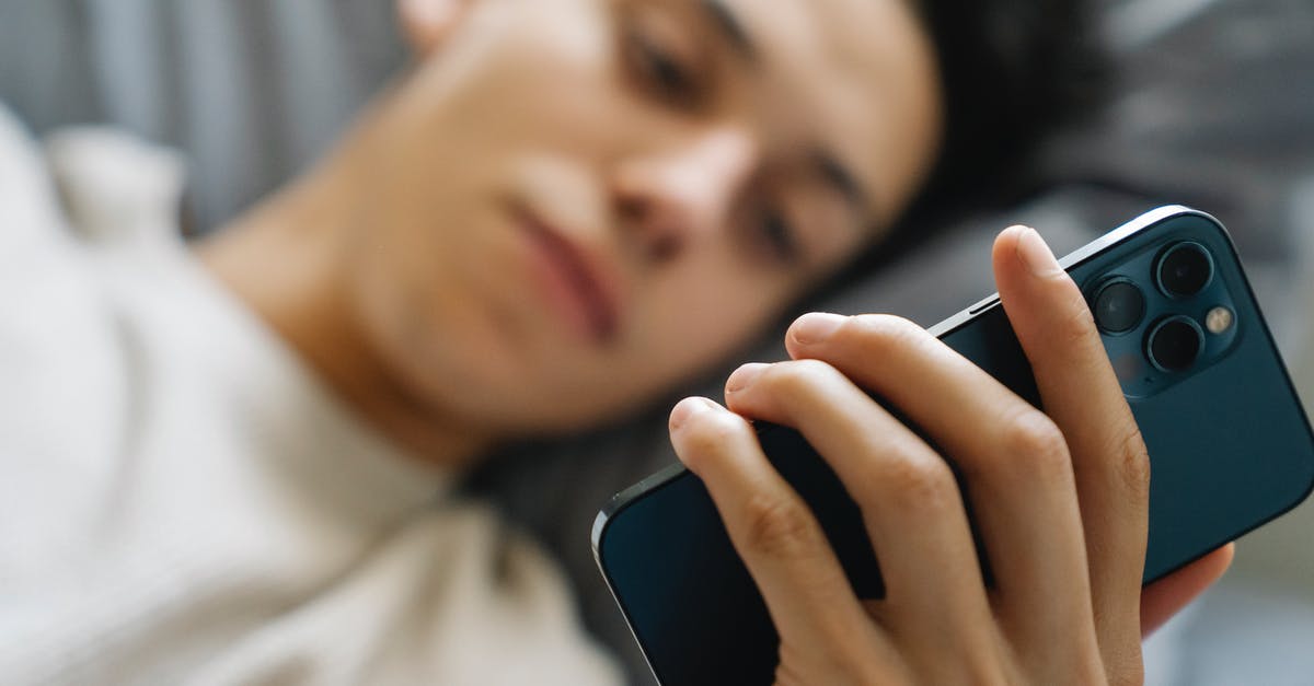 JFK Alaska Lounge time limit with Priority Pass - Soft focus of young guy lying on bed and using modern smartphone in weekend morning at home