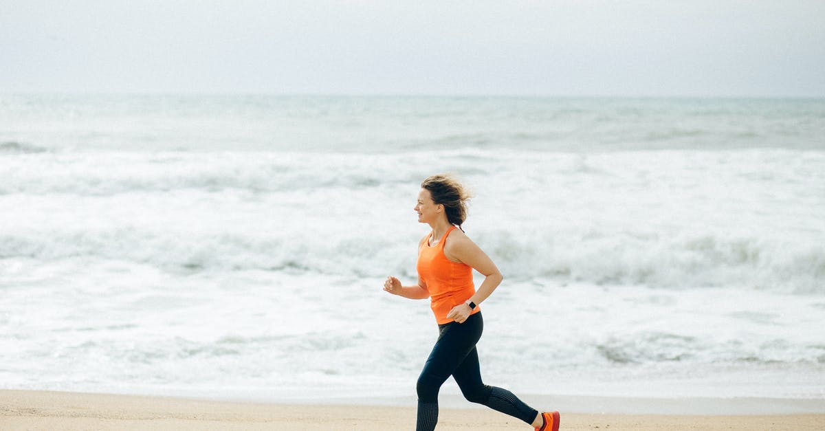 Jogging in Tokyo and Osaka - Woman in White Tank Top and Black Leggings Running on Beach