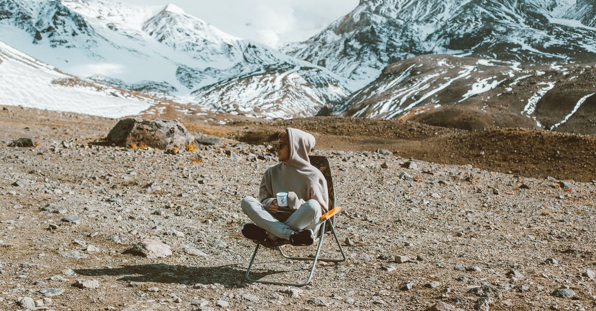 Judo experience in Tokyo (for a day or two) - Full body of man sitting on folding chair and drinking tea with high mountains covered with snow on background