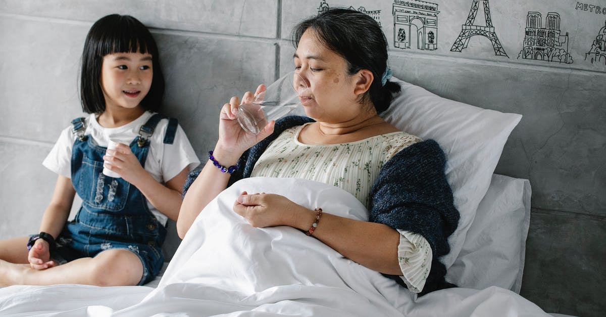 Just what is unhealthy in the water in Mexico? - Adorable ethnic child giving pills to unhealthy grandmother drinking water in bed