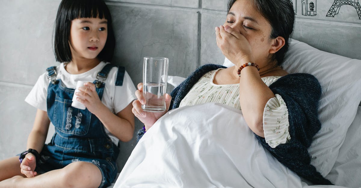 Just what is unhealthy in the water in Mexico? - Cute Asian little girl sitting on soft bed and looking at sick grandmother drinking medicine on sunny day