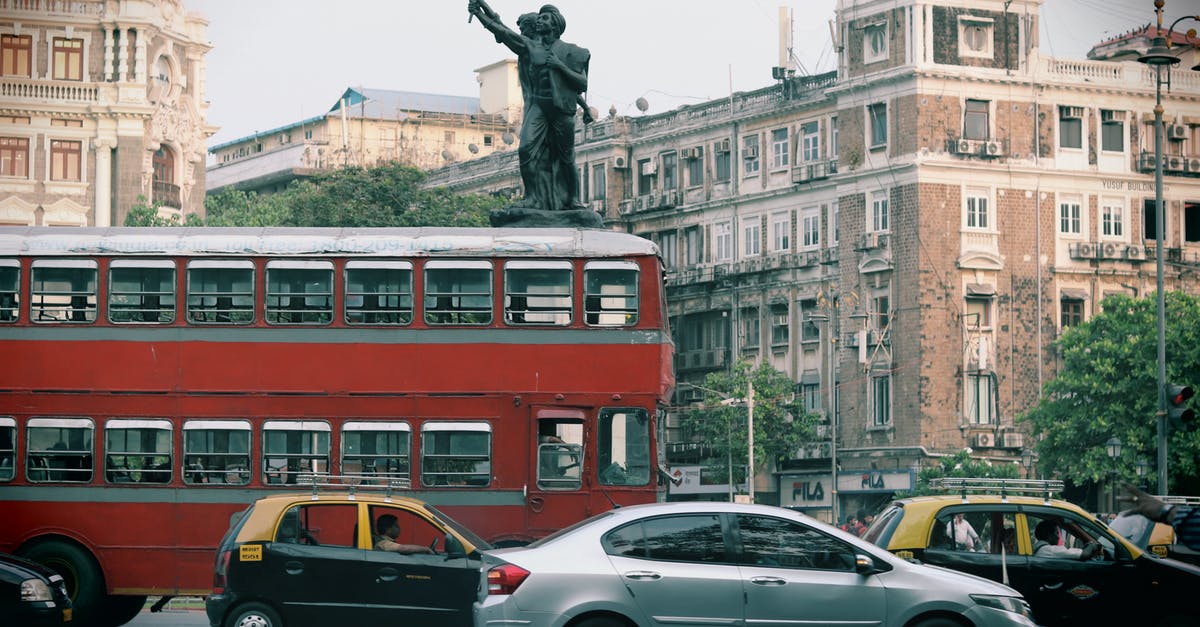 La Paz to Santiago by bus - Man in Black Jacket Standing Beside Silver Sedan Near Red Double Decker Bus