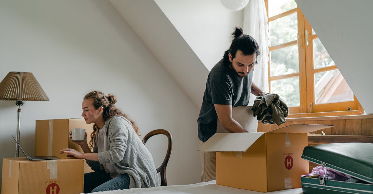 Laptop in a suitcase - Ethnic boyfriend unpacking box while woman using laptop at home