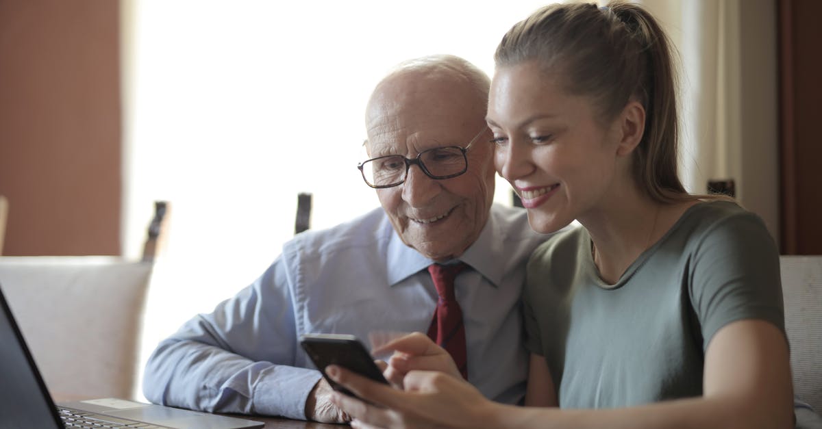 Laptop in cargo hold insurance coverage [duplicate] - Smiling young woman in casual clothes showing smartphone to interested senior grandfather in formal shirt and eyeglasses while sitting at table near laptop